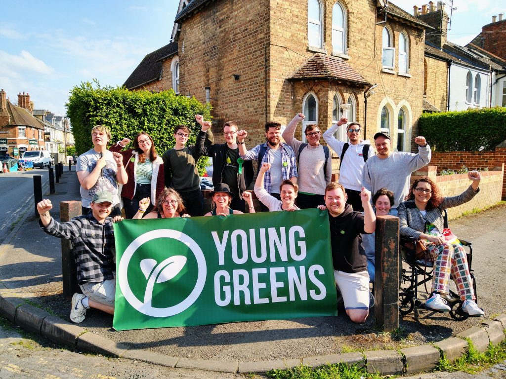 Oxford Action Day 2022 Group of Young Greens in Oxford with the Young Greens banner. They're all smiling with their fists raised